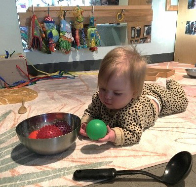 baby plays with a ball on the floor