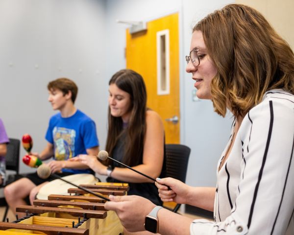 Student plays a wooden xylophone in a music education class at the Conservatory.