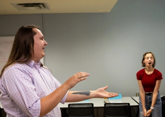 A music educator teaches vocal students in a classroom.